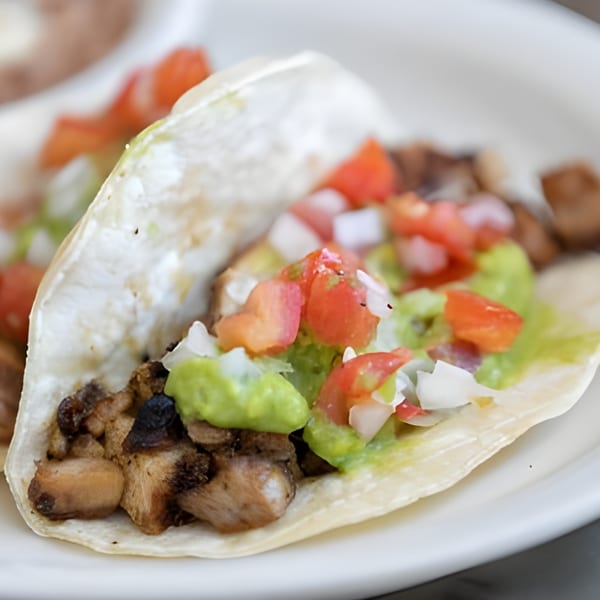 Habanero's Fresh Mex taco with grilled meat, guacamole, diced tomatoes, and onions on a white plate.